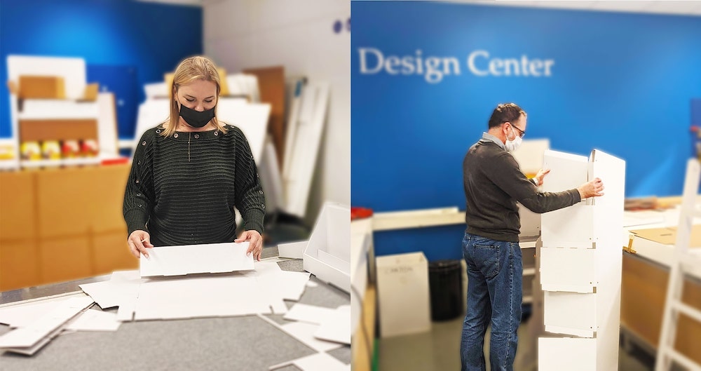 Twee designers van het Smurfit Kappa Drogenbos team aan het werk met hun handen met het design van een point of sale display.